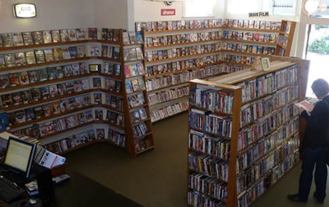 A person is browsing dvds in a video store in one of the last standing video stores in Aotearoa